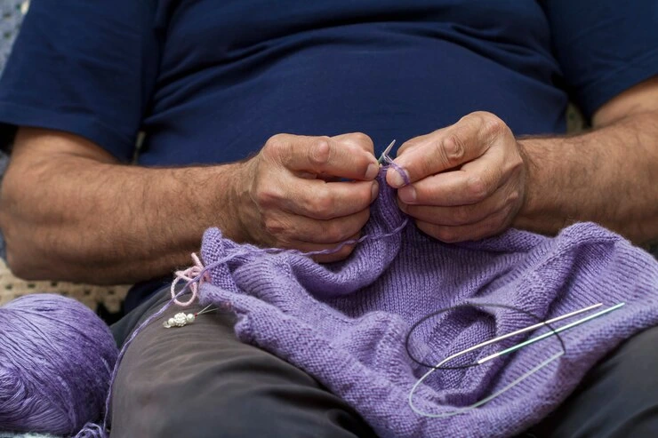 mann som strikker en lilla genser